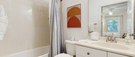 A bathroom with a bathtub, toilet, and vanity with a mirror.