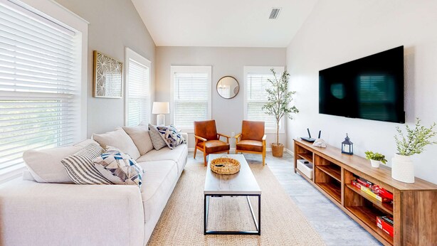 Ein Wohnzimmer mit einer Couch, zwei Sesseln, einem Couchtisch, einem Fernseher und einer Holz-Unterhaltungseinrichtung.