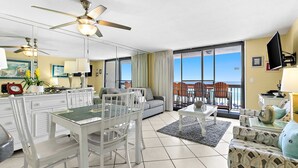 Een ruime woonkamer met een eettafel, stoelen, een bank en een balkon met uitzicht.