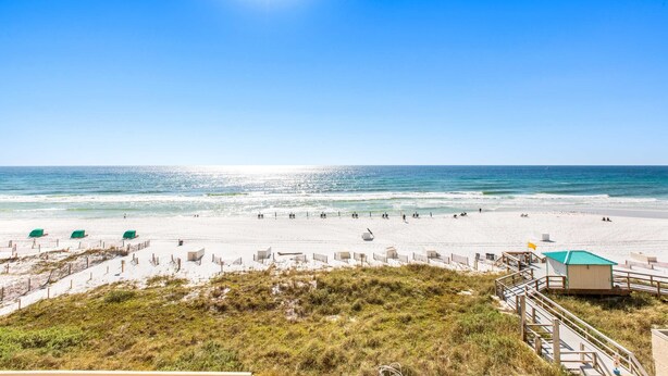 Een strand met een heldere lucht, zandstrand en een redderpost.