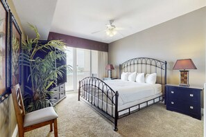 A bedroom with a bed, a chair, a nightstand, a lamp, and a large plant. - Family-friendly 13th-floor condo w/furnished balcony, shared tennis, and pool (Miramar Beach)