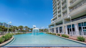 A swimming pool with a central fountain, surrounded by a brick walkway and palm trees. - Family-friendly 13th-floor condo w/furnished balcony, shared tennis, and pool (Miramar Beach)
