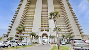 A tall, beige multi-story hotel with a symmetrical facade, featuring balconies and a central entrance. - Family-friendly 13th-floor condo w/furnished balcony, shared tennis, and pool (Miramar Beach)