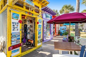 Une boutique aux couleurs vives, sur le thème de la plage, avec une terrasse en bois, une table et des chaises.