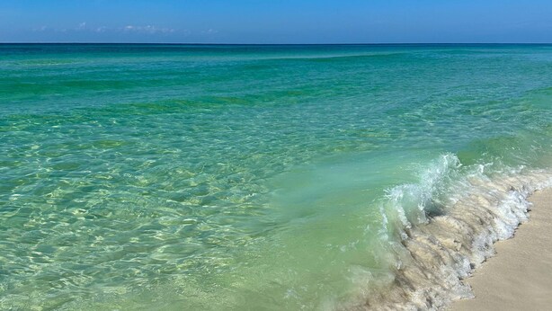 Ein Strand mit klarem türkisblauem Wasser und einem Sandstrand.
