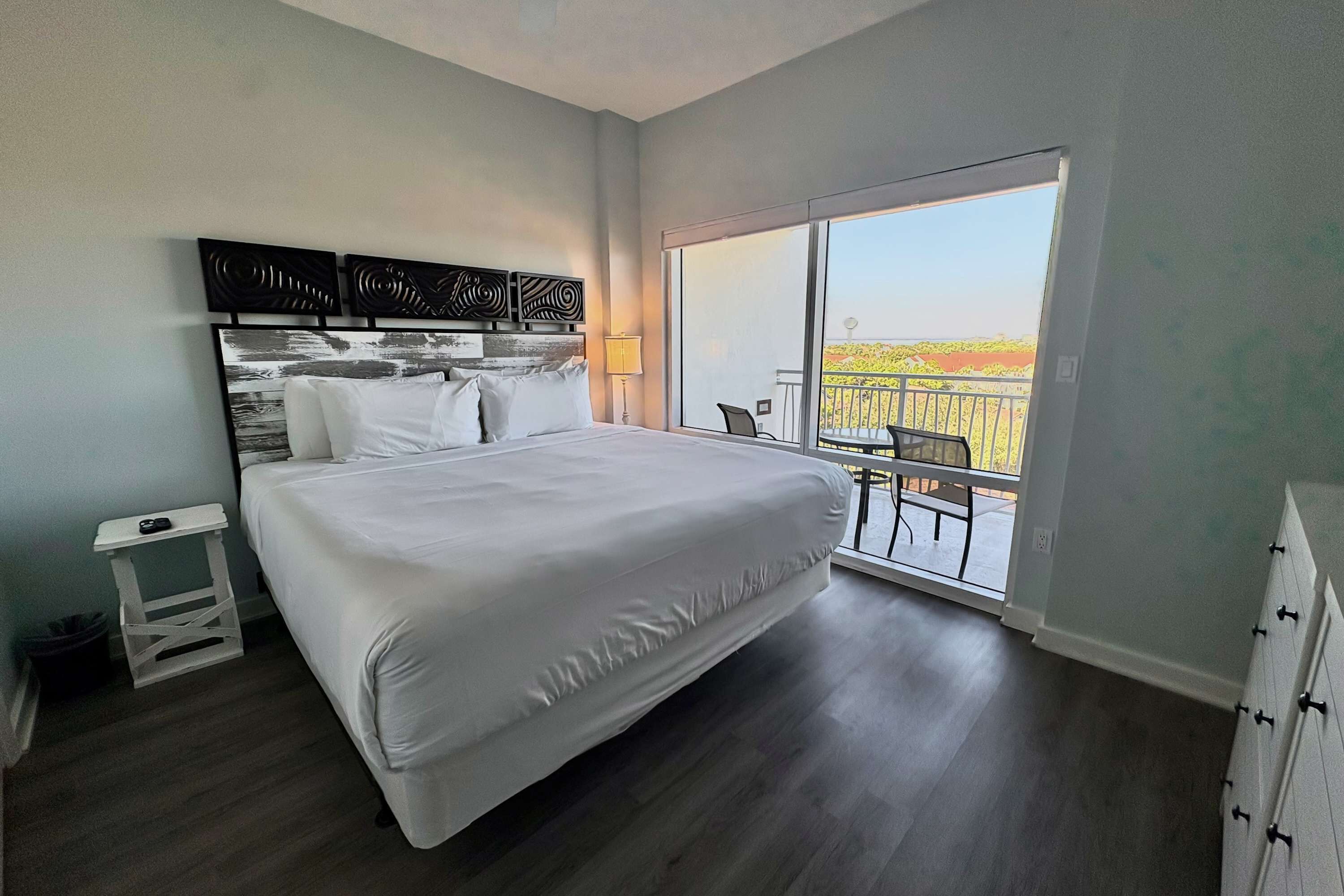 Une chambre d’hôtel moderne avec un grand lit, une petite table et un balcon offrant une vue agréable.