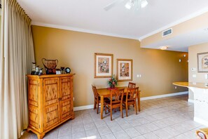 A dining area with a wooden table and chairs, a cabinet with decorative items, and framed pictures on the wall. - Welcoming 6th Floor Condo Incredible Gulf-Front Views Near Local Activities (Fort Walton Beach)