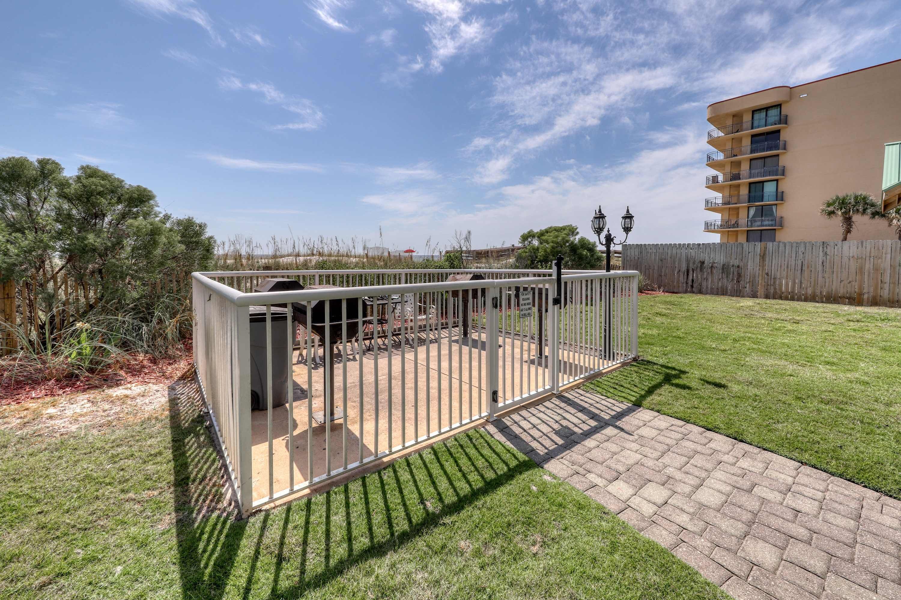 Ein eingezäunter Außenbereich mit Terrasse, Holzlattenzaun und einem Gebäude im Hintergrund.