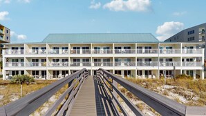 Un hotel de varios pisos con balcones y un paseo marítimo de madera que conduce al mismo.
