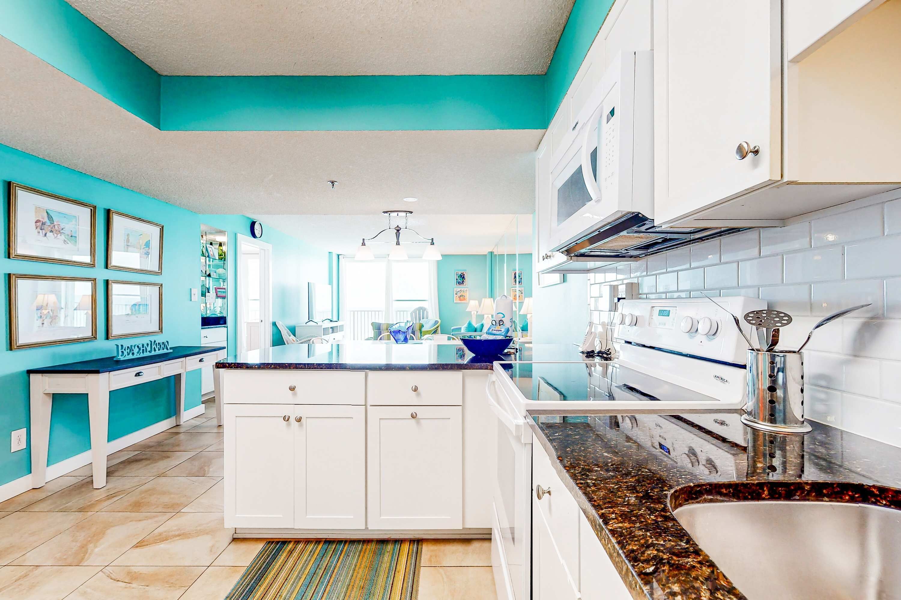 A modern kitchen with white cabinets, a granite countertop, and a stainless steel sink.