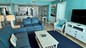 A living room with a sofa, coffee table, and a TV stand. - Beach front condo with washer&dryer, shared pool and beach access (Santa Rosa Beach)