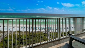 A balcony with a view of a beach with umbrellas and a clear sky. - Beach front condo with washer&dryer, shared pool and beach access (Santa Rosa Beach)