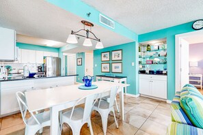 Une cuisine moderne avec des meubles blancs, un îlot central et un coin repas avec des chaises blanches.