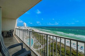 Een balkon met uitzicht op strand en zee.