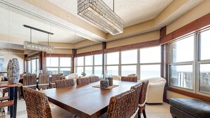 Un comedor espacioso con una larga mesa de madera, sillas de mimbre y una lámpara moderna.