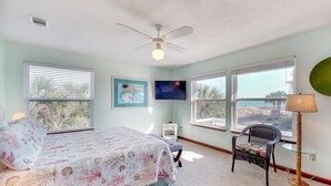 A bedroom with a bed, a chair, a TV, and a window with a view. - Beachside home with private pool & amazing views (St. George Island)