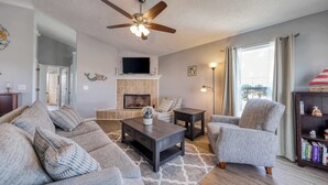 A living room with a fireplace, a ceiling fan, and a bookshelf. - Dog-friendly coastal home with a game room and covered patio (Port St. Joe)