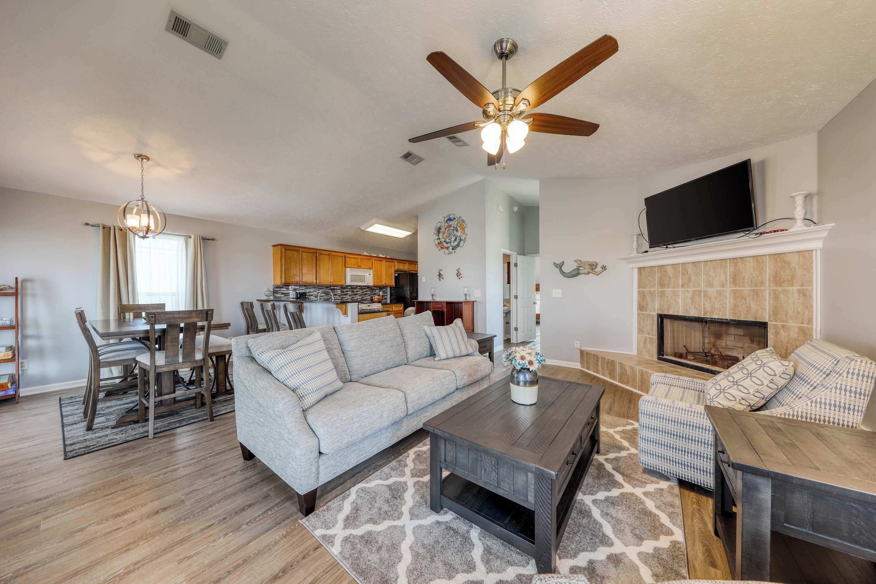 A living room with a sofa, coffee table, and fireplace. There is a television mounted above the fireplace.