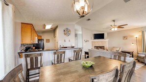 A spacious dining area with a wooden table and chairs, a kitchen in the background, and a ceiling fan. - Dog-friendly coastal home with a game room and covered patio (Port St. Joe)