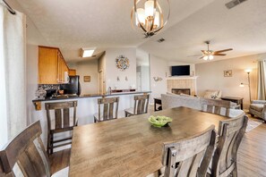 A spacious dining area with a wooden table and chairs, a kitchen in the background, and a ceiling fan. - Dog-friendly coastal home w/ a game room and covered patio (Port St. Joe)