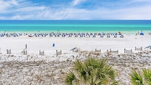 A beach with numerous umbrellas and people. - Seaside condo with wonderful beach views, balcony, grill, pool, hot tub, & gym (Fort Walton Beach)