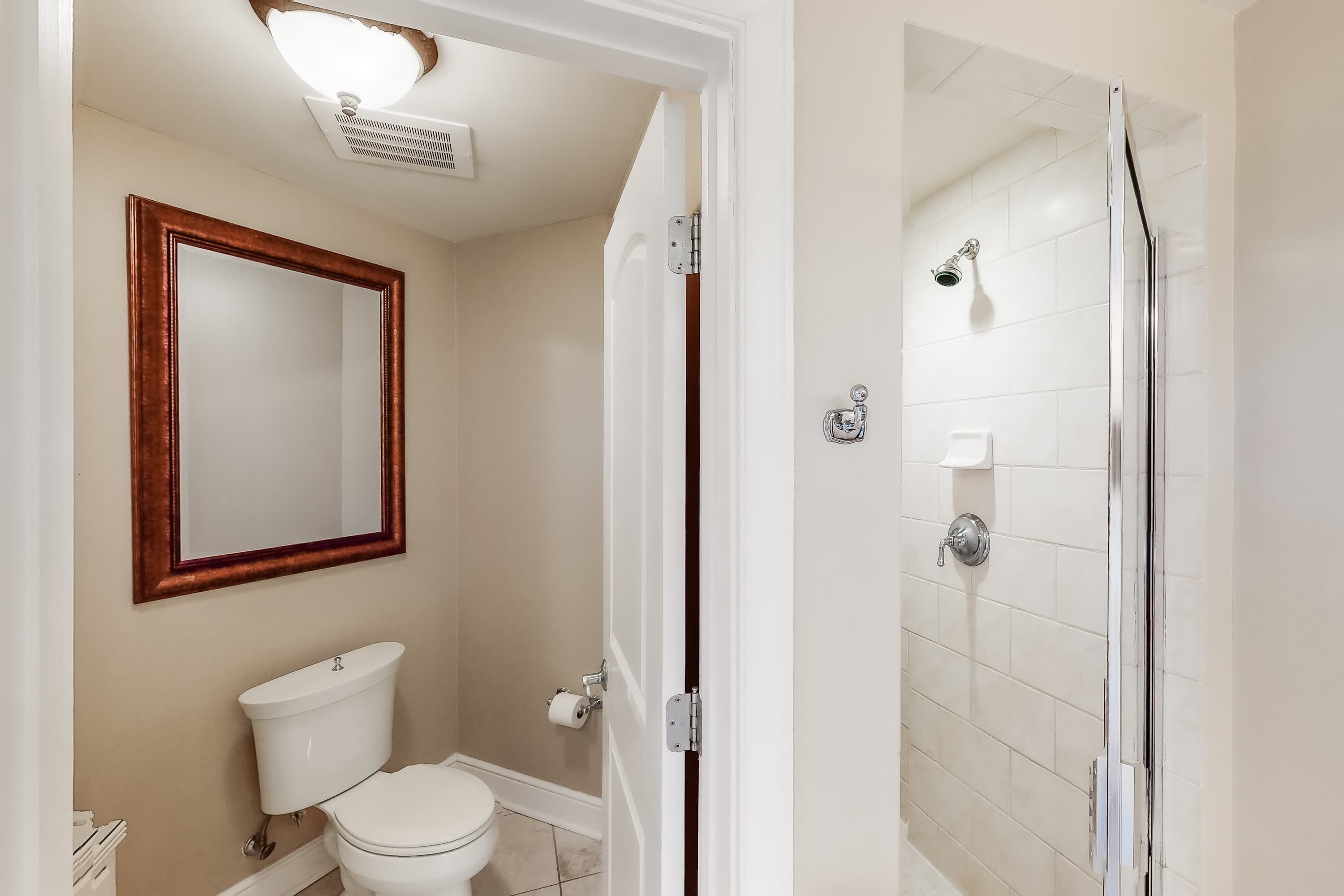 Een badkamer met toilet, spiegel en douche.