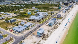 Luchtbeeld van een kustgebied met woningen, een strand en een weg.