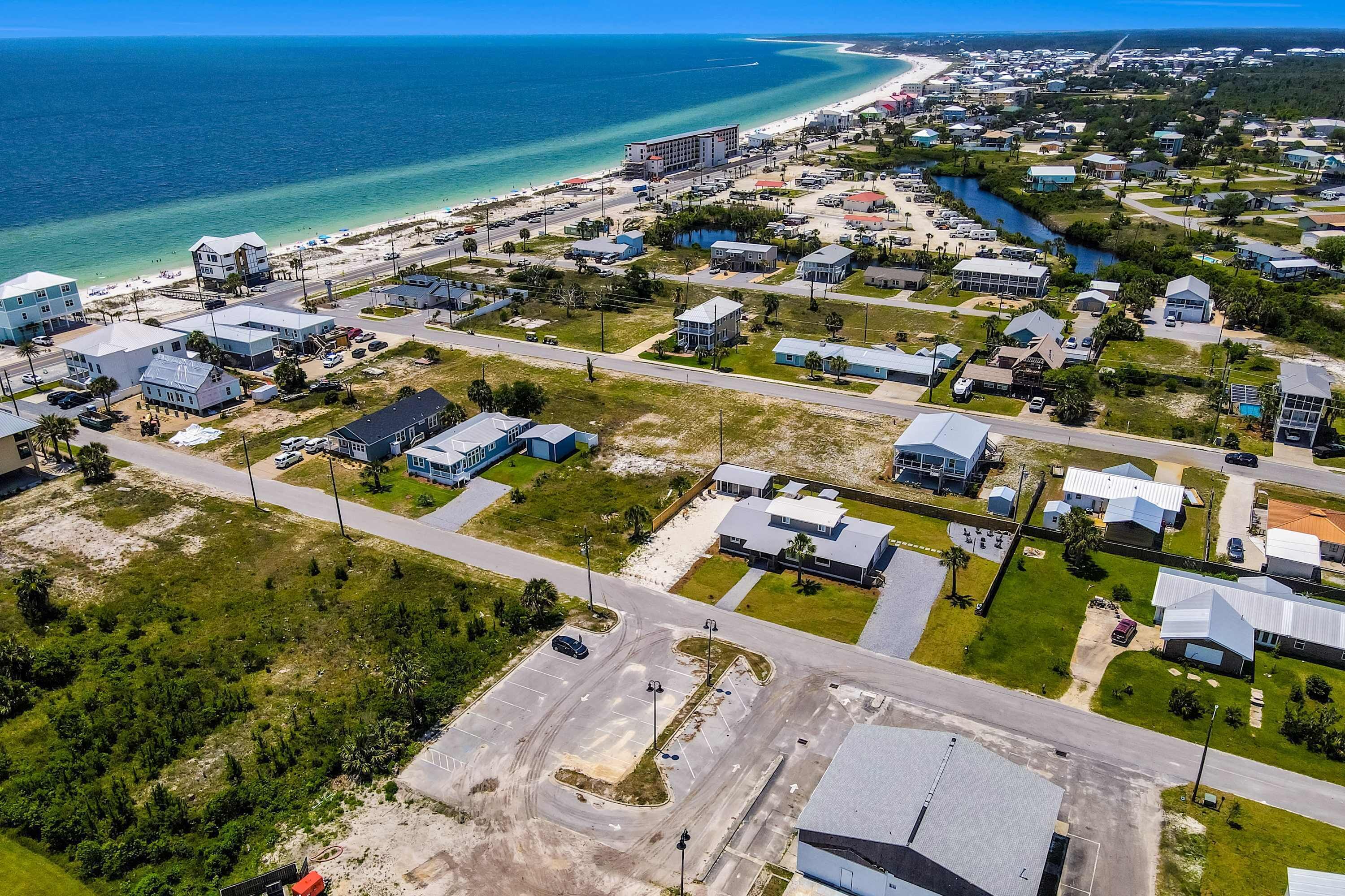 Vue aérienne d’une zone résidentielle côtière, avec des maisons, des routes et une plage.
