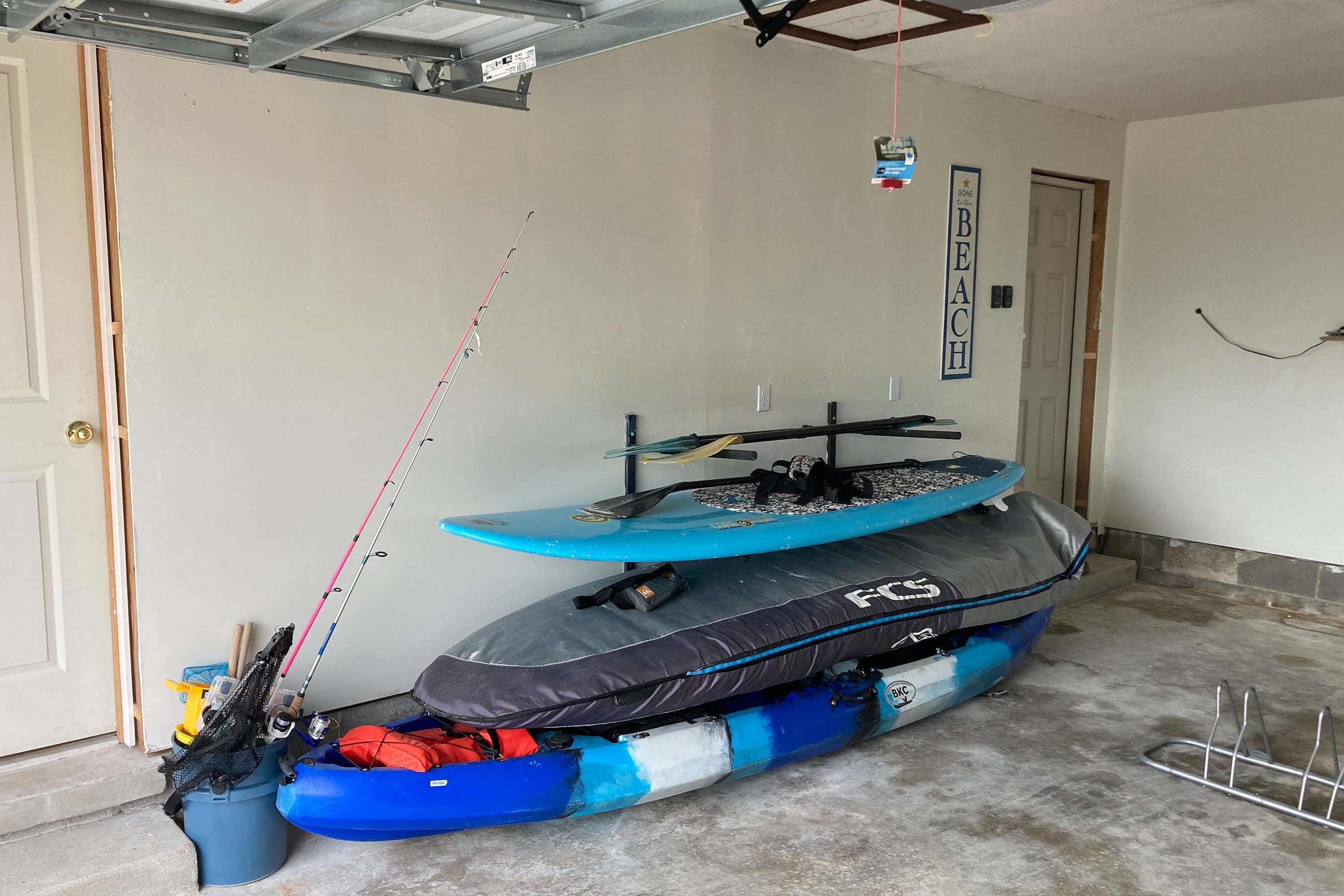 A garage with kayaks and a fishing rod.