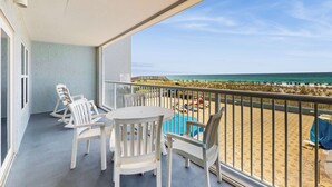 A balcony with a view of the beach, white chairs, and a table. - Beautiful beachfront condo with shared pool & beach access! (Fort Walton Beach)