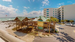 A beachfront hotel with a wooden beach hut, a covered seating area, and a parking lot. - Beautiful beachfront condo with shared pool & beach access! (Fort Walton Beach)