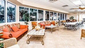 A spacious indoor area with a long dining table, multiple chairs, and a sofa. - Beautiful beachfront condo with shared pool & beach access! (Fort Walton Beach)