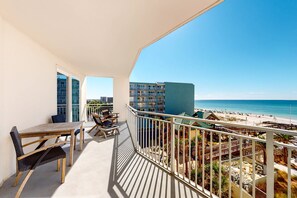 A balcony with a view of the beach, a dining table, and chairs. - Blu 400 - Spacious, gulf-front condo with resort amenities -  near restaurants (Fort Walton Beach)