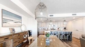 Uma cozinha moderna com armários brancos, uma ilha central e iluminação pendente.