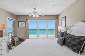 A bedroom with a bed, a chair, a desk, a ceiling fan, and a view of the ocean. - Spacious beachfront condo with full kitchen, shared pool and beach access (Fort Walton Beach)