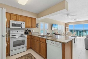 A modern kitchen with wooden cabinets, a built-in microwave, and a dishwasher. - Spacious beachfront condo with full kitchen, shared pool and beach access (Fort Walton Beach)