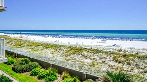 Blick auf einen Strand mit blauem Himmel, sandigem Ufer und einem Gebäude mit Balkon, das auf den Ozean blickt.