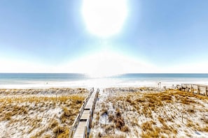 A beach with a wooden boardwalk leading to the water, sandy dunes, and a clear sky. - 3rd Floor Bright Gulf-Front Condo with Views, Close To Entertainment (Fort Walton Beach)