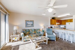 A living room with a sofa, coffee table, and a dining area with a bar and chairs. - 3rd Floor Bright Gulf-Front Condo with Views, Close To Entertainment (Fort Walton Beach)