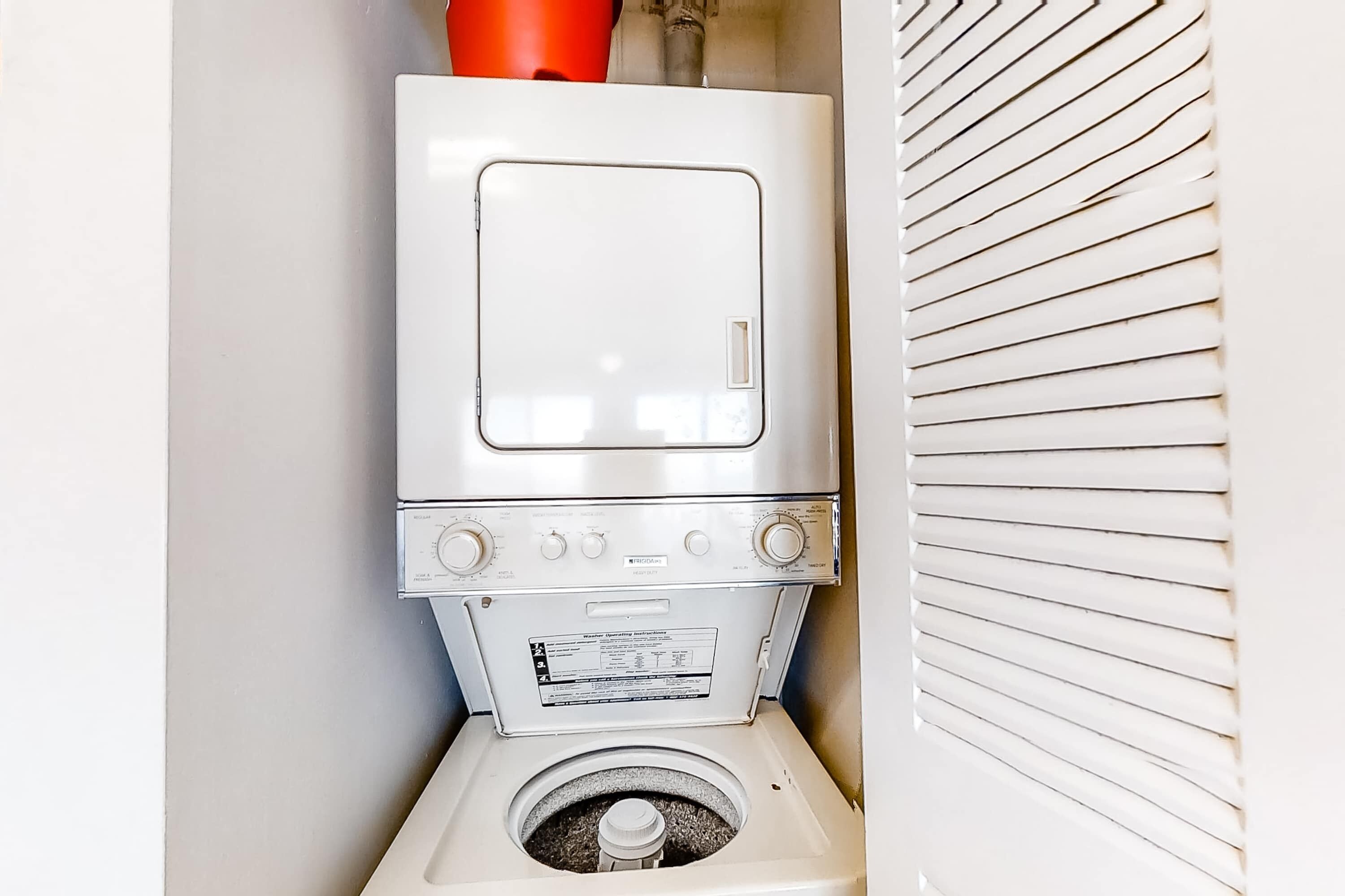 A compact, white laundry room with a stacked washer and dryer.