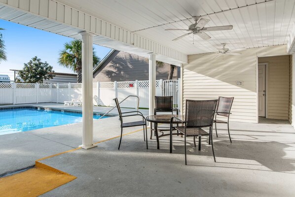 A covered outdoor area with a pool, chairs, and a table. - Family-Friendly Home w/ Shared Pool, High-Speed WiFi, Washer/Dryer, & Central AC (Mexico Beach)