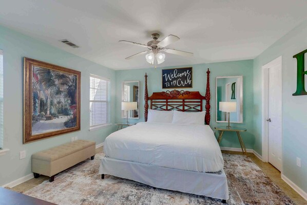A bedroom with a four-poster bed, a large framed painting, a bench, and a ceiling fan. - Family-Friendly Home w/ Shared Pool, High-Speed WiFi, Washer/Dryer, & Central AC (Mexico Beach)