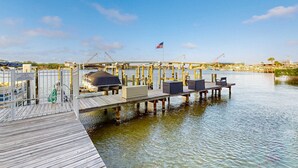 Un muelle con zona de estar techada, una bandera y vistas al agua.