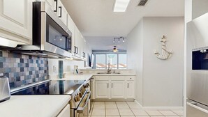 Una cocina moderna con gabinetes blancos, estufa de acero inoxidable y salpicadero de azulejos.