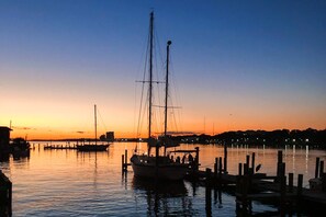 Un port tranquille au coucher du soleil, avec des bateaux amarrés et un ciel dégagé.