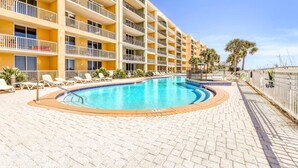 Ein Hotel mit Swimmingpool, Liegestühlen und einer Palme.