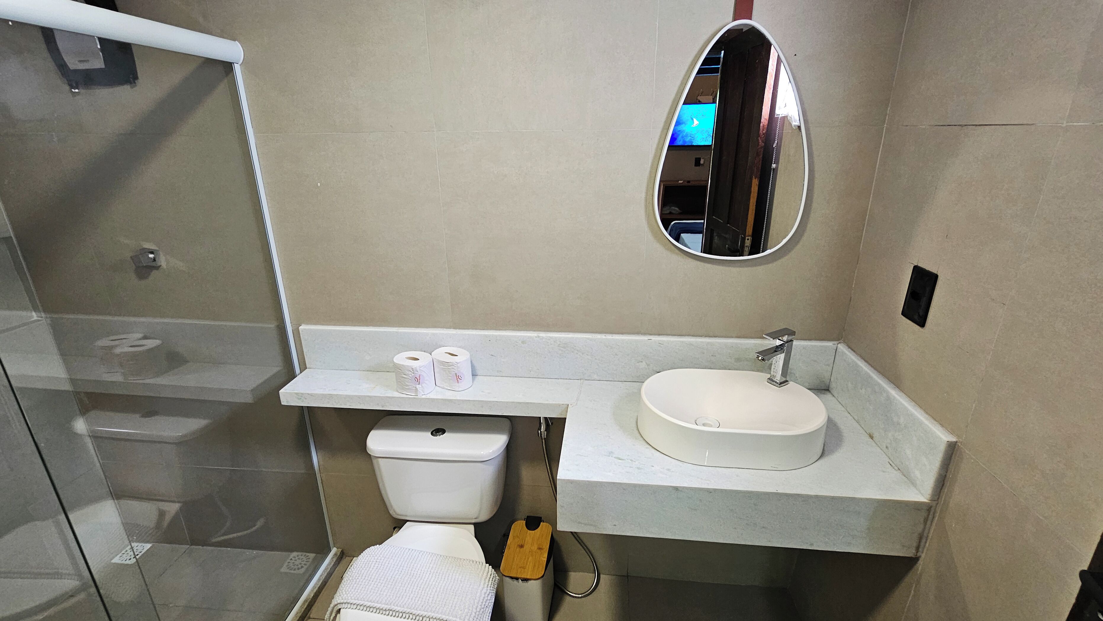 Baño con inodoro, lavamanos, espejo y ducha.