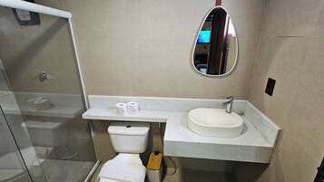 Baño con inodoro, lavamanos, espejo y ducha.