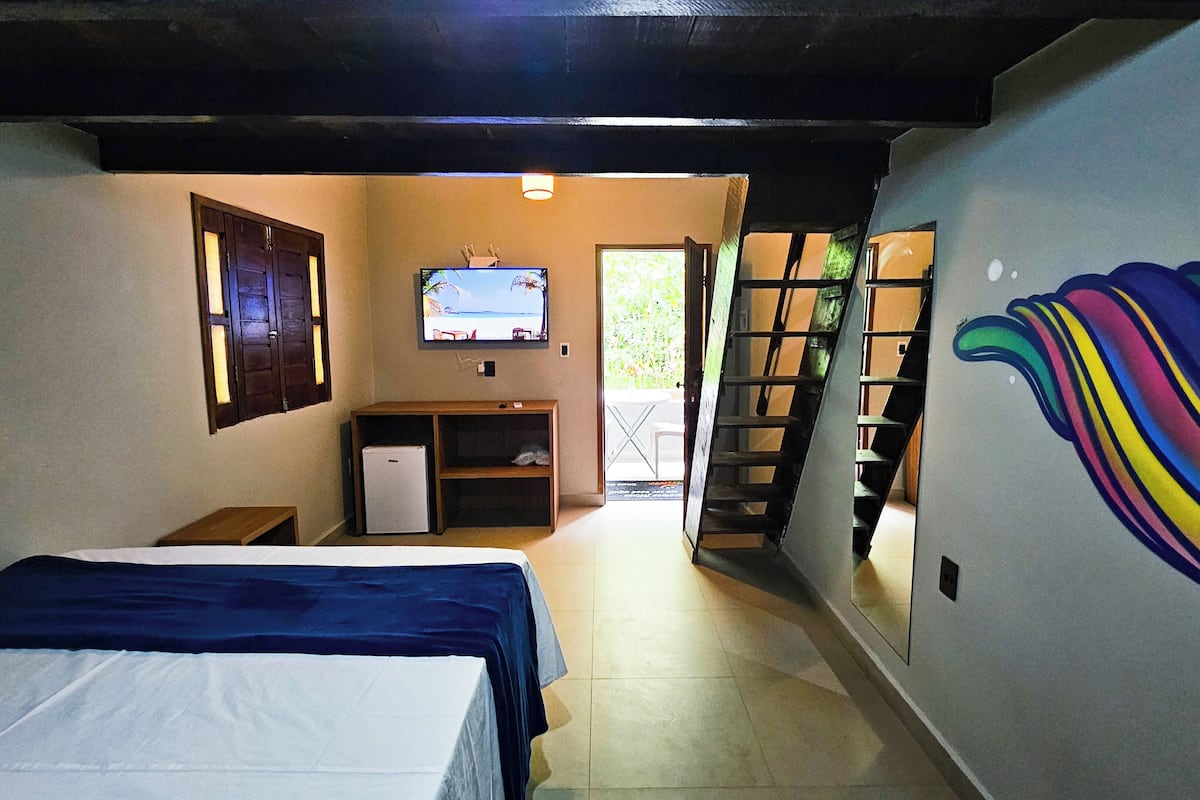 A narrow hallway with two beds, a TV, a small fridge, and a door leading outside.