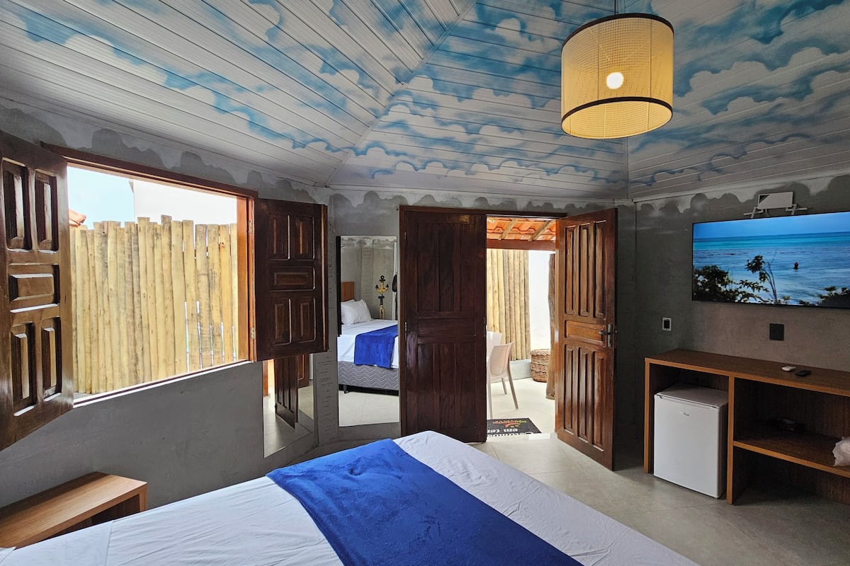 A bedroom with a bed, a TV, a desk, and a wardrobe.